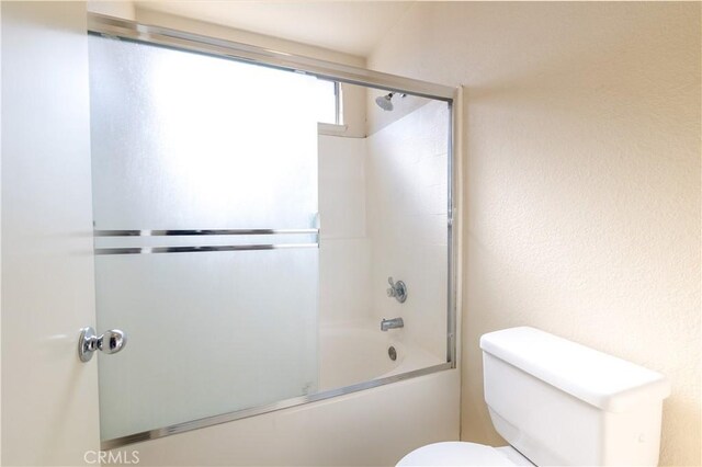 bathroom featuring shower / bath combination with glass door and toilet