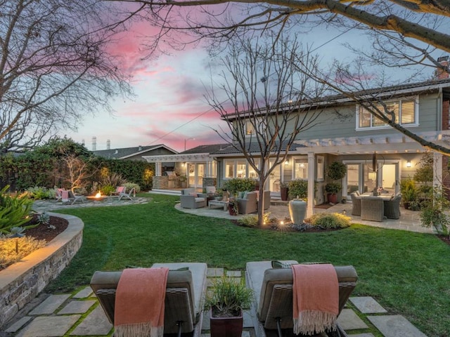 back house at dusk with an outdoor living space with a fire pit, a yard, and a patio