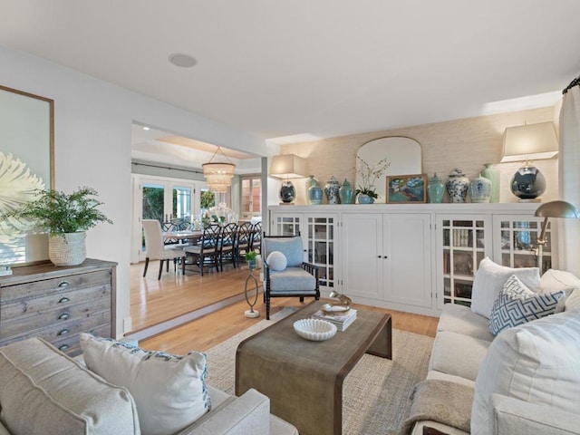 living room featuring french doors, a notable chandelier, and light hardwood / wood-style floors