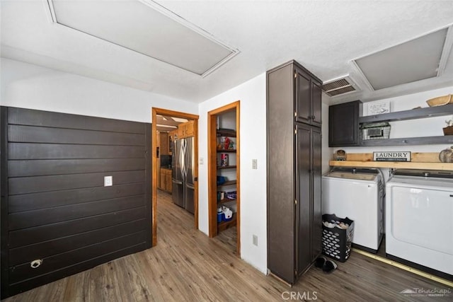 laundry area with light wood-type flooring, washer and dryer, and cabinets