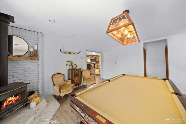 playroom featuring a wood stove, billiards, and light hardwood / wood-style flooring