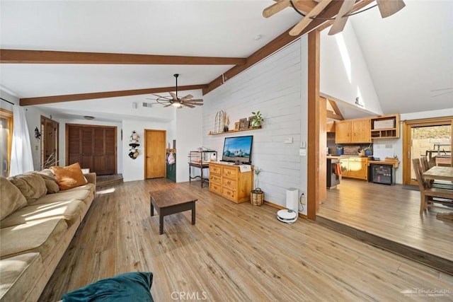 living room with vaulted ceiling with beams, wooden walls, and light hardwood / wood-style floors