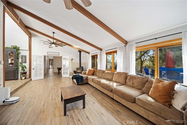 living room featuring light hardwood / wood-style floors, a wood stove, french doors, high vaulted ceiling, and beamed ceiling