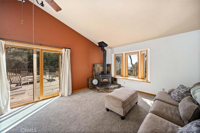 living room featuring vaulted ceiling, a wood stove, and carpet floors