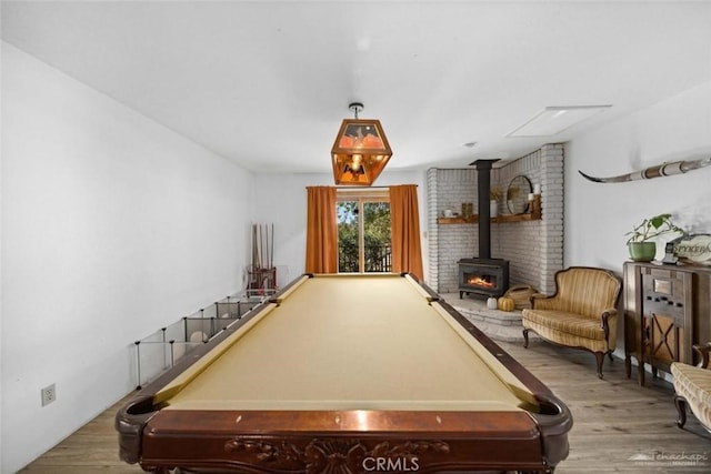 recreation room featuring pool table, a wood stove, and wood-type flooring