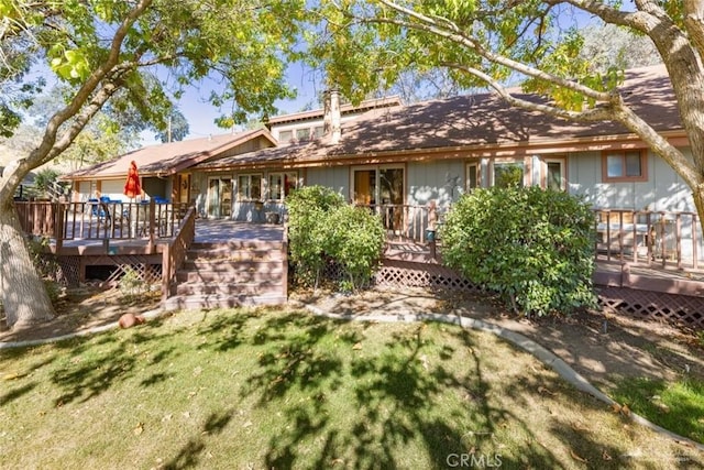 rear view of property featuring a wooden deck and a lawn