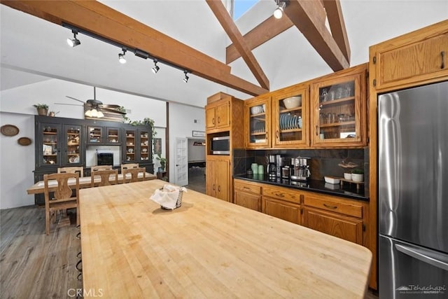 kitchen featuring tasteful backsplash, lofted ceiling with skylight, dark wood-type flooring, appliances with stainless steel finishes, and rail lighting