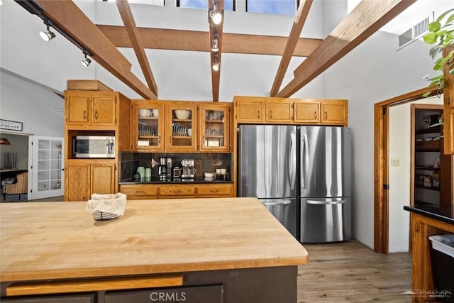 kitchen with pendant lighting, stainless steel appliances, tasteful backsplash, vaulted ceiling with beams, and light hardwood / wood-style flooring