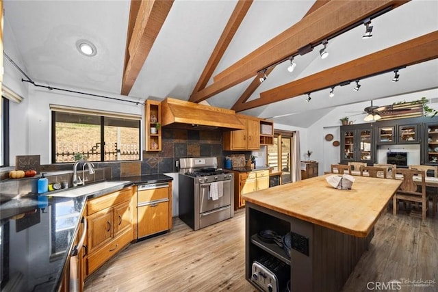 kitchen with tasteful backsplash, ceiling fan, a kitchen island, lofted ceiling with beams, and stainless steel range with gas cooktop