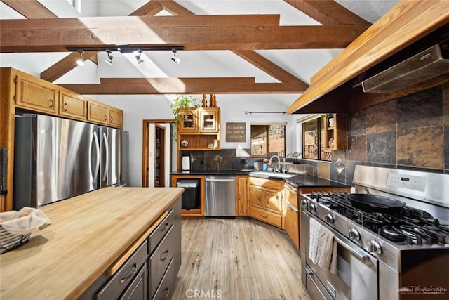 kitchen featuring premium range hood, appliances with stainless steel finishes, decorative backsplash, vaulted ceiling with beams, and sink