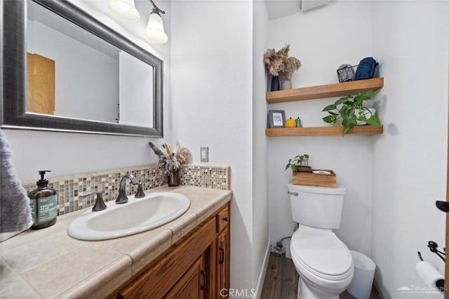 bathroom featuring decorative backsplash, hardwood / wood-style flooring, toilet, and vanity