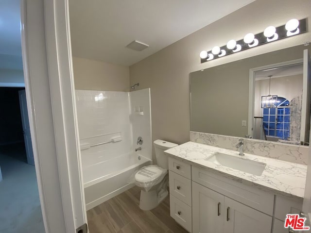 full bathroom featuring toilet, vanity, bathing tub / shower combination, hardwood / wood-style flooring, and an inviting chandelier