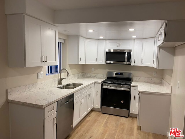 kitchen with sink, stainless steel appliances, white cabinets, and light stone countertops