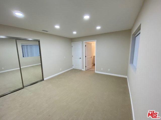 unfurnished bedroom with light colored carpet and ensuite bathroom