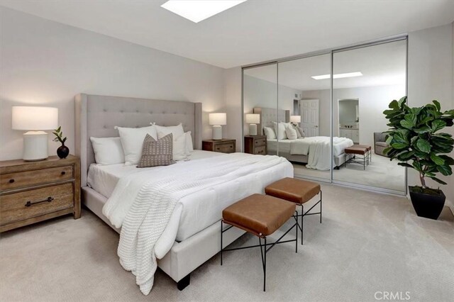 bedroom featuring a closet, a skylight, and light colored carpet