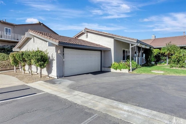 view of front of home with a garage, driveway, a tiled roof, and stucco siding