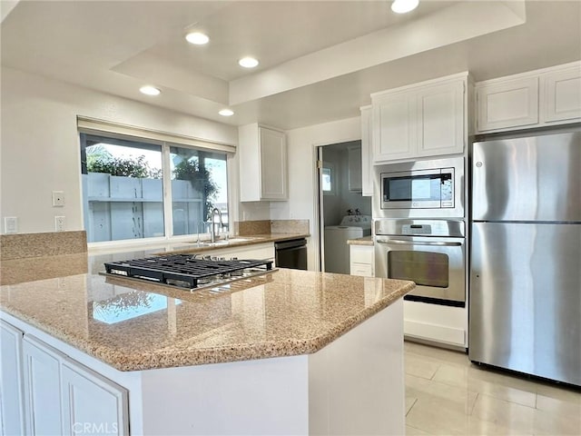 kitchen with white cabinets, a raised ceiling, light stone counters, stainless steel appliances, and a sink