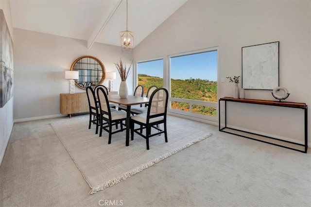 dining area featuring high vaulted ceiling, light carpet, a notable chandelier, and baseboards