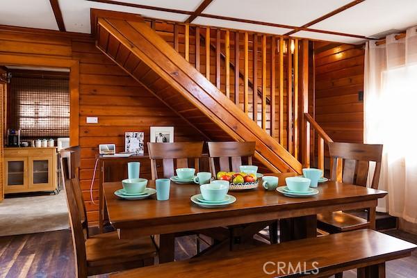 dining space with wood walls and wood-type flooring