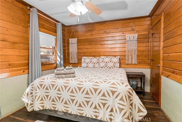 bedroom featuring ceiling fan, dark hardwood / wood-style flooring, and wooden walls