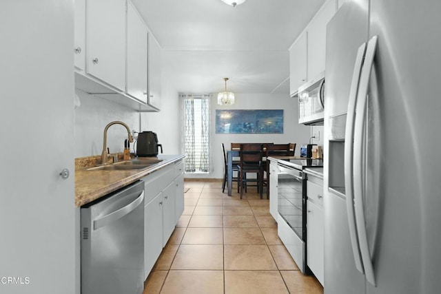 kitchen featuring appliances with stainless steel finishes, hanging light fixtures, light tile patterned floors, white cabinets, and sink