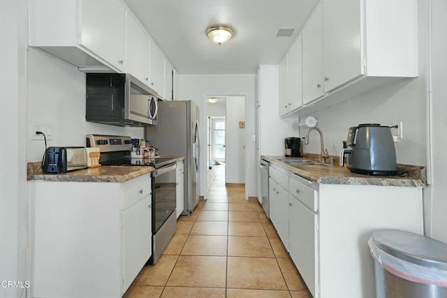 kitchen with sink, white cabinets, light tile patterned flooring, and appliances with stainless steel finishes