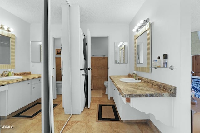 bathroom with toilet, tile patterned floors, vanity, and a textured ceiling