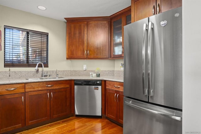 kitchen featuring light stone counters, sink, stainless steel appliances, and light wood-type flooring