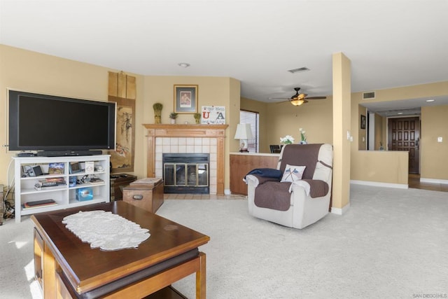 carpeted living room with ceiling fan and a tiled fireplace