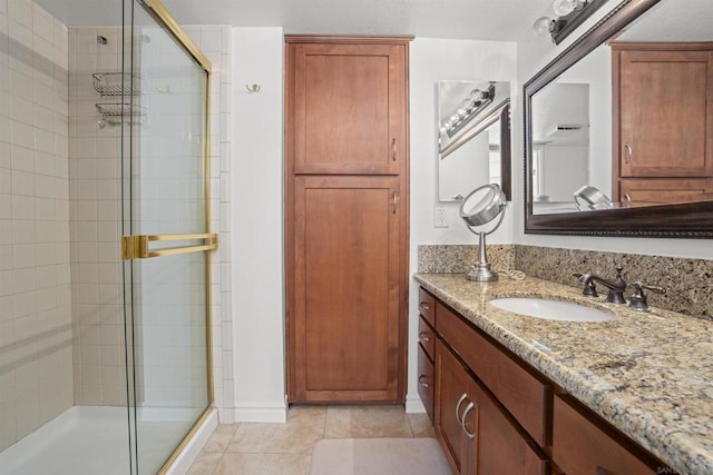 bathroom with a shower with shower door, vanity, and tile patterned flooring