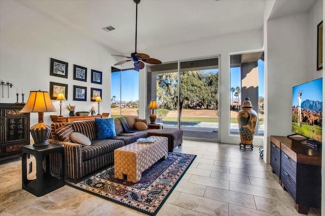 living room featuring light tile patterned floors, ceiling fan, and a high ceiling