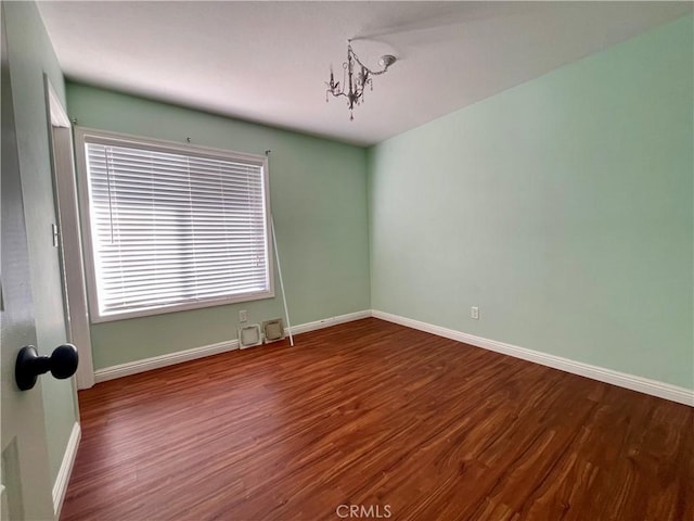 spare room featuring a notable chandelier and hardwood / wood-style flooring