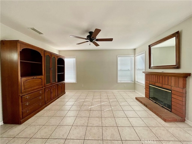 unfurnished living room featuring ceiling fan, a fireplace, and light tile patterned flooring