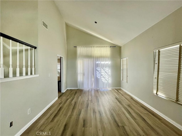 unfurnished room featuring wood-type flooring and high vaulted ceiling