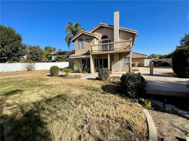 back of house with a deck and a lawn