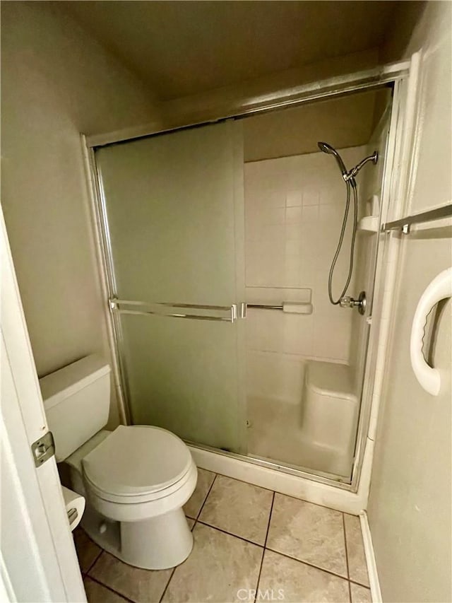 bathroom featuring toilet, tile patterned floors, and walk in shower