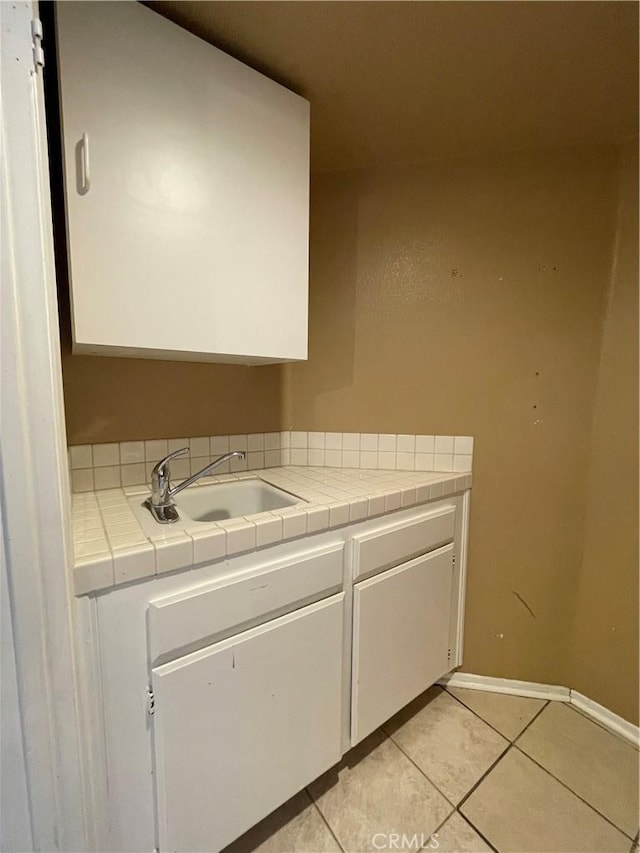 laundry area featuring light tile patterned flooring and sink