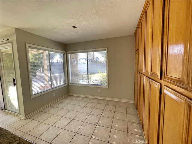 unfurnished dining area with a textured ceiling and light tile patterned floors