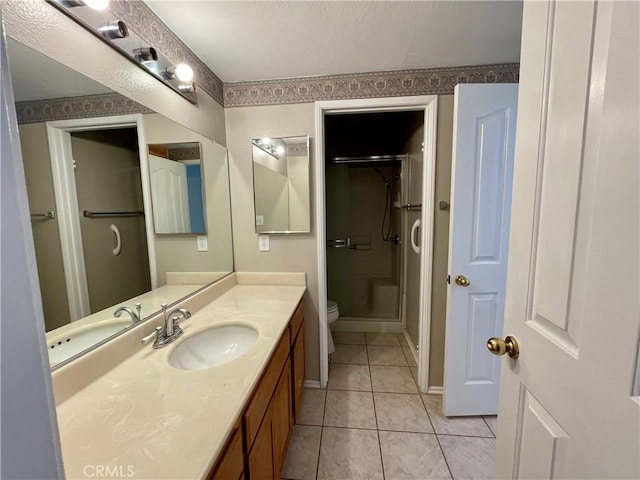 bathroom featuring tile patterned floors, a shower with door, toilet, and vanity