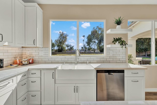 kitchen with white cabinetry, sink, stainless steel dishwasher, and light stone counters