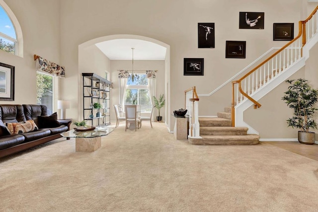 carpeted living room featuring a towering ceiling and a chandelier