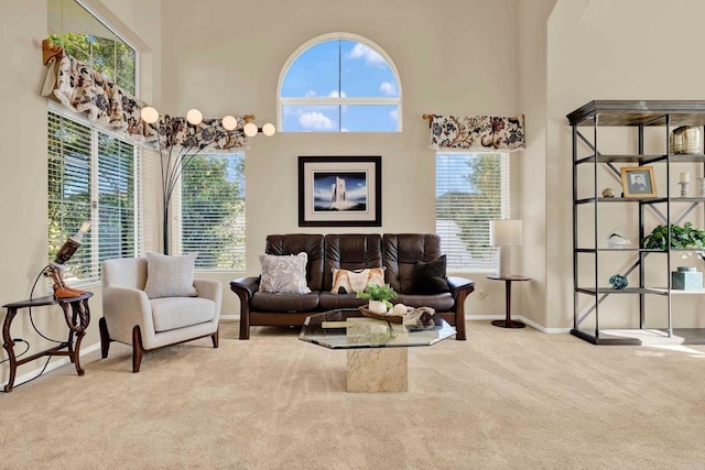 living area with a towering ceiling, a healthy amount of sunlight, and carpet