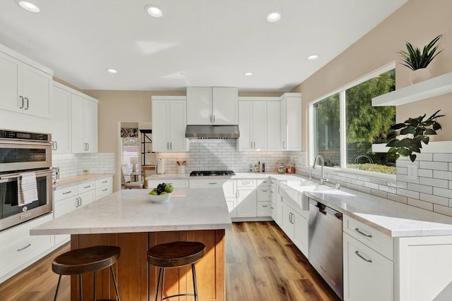 kitchen with a breakfast bar area, plenty of natural light, stainless steel appliances, white cabinets, and a kitchen island