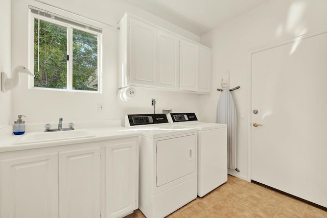 washroom with cabinets, washing machine and clothes dryer, and sink