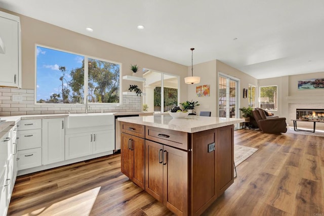 kitchen featuring white cabinetry, sink, backsplash, and hanging light fixtures