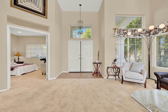 entryway with light colored carpet, a chandelier, and a high ceiling