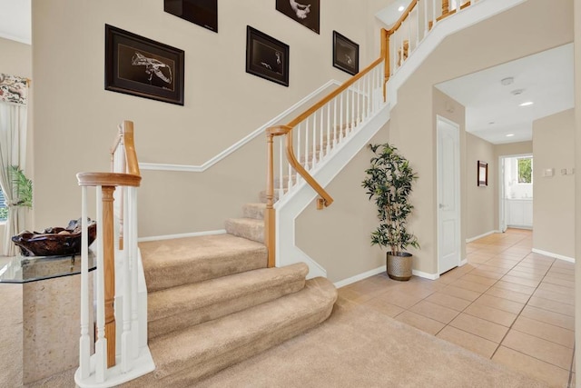 stairway with tile patterned flooring and a high ceiling