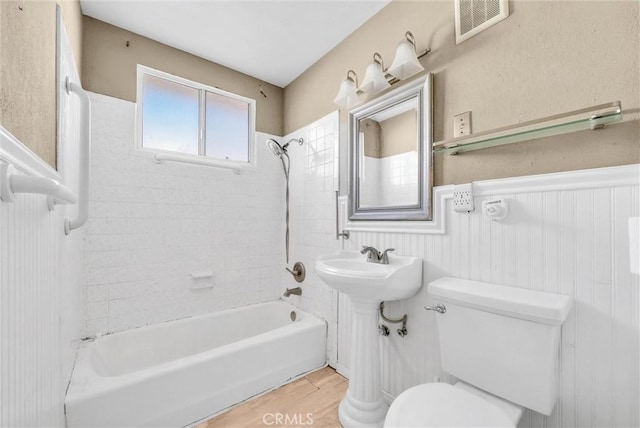 bathroom featuring tiled shower / bath, toilet, and wood-type flooring