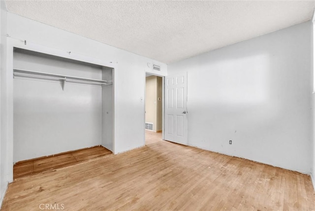 unfurnished bedroom featuring a textured ceiling, a closet, and wood-type flooring