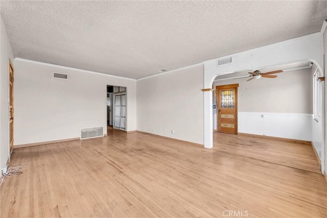 spare room with ceiling fan, a textured ceiling, ornamental molding, and light hardwood / wood-style floors